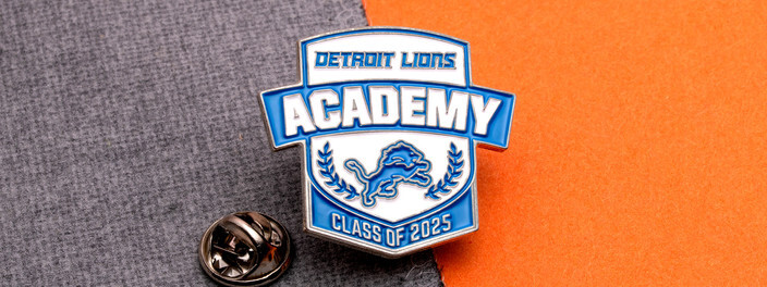 Black and purple CMA Class of 2025 pin with a gold pharaoh mask, on a white strap