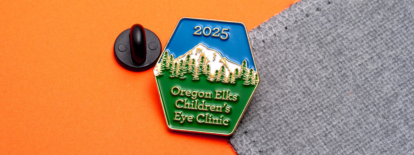Hexagon pin reading Oregon Elks Children's Eye Clinic 2025 under a snowy mountain and pine trees