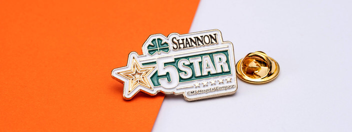 Green and white Shannon 5 Star pin with a gold star and a clover, beside a gold clutch