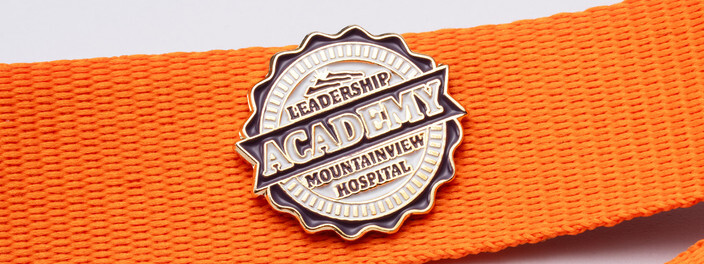 Purple and white Leadership Academy pin for Mountainview Hospital on an orange lanyard
