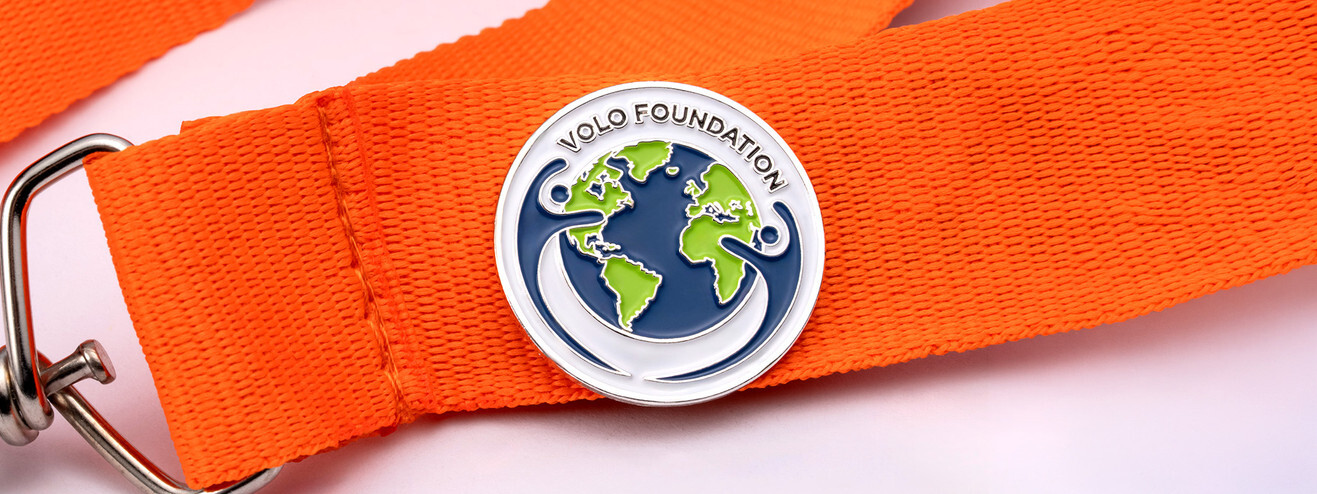 Round foundation pin with a blue and green globe, pinned to an orange lanyard
